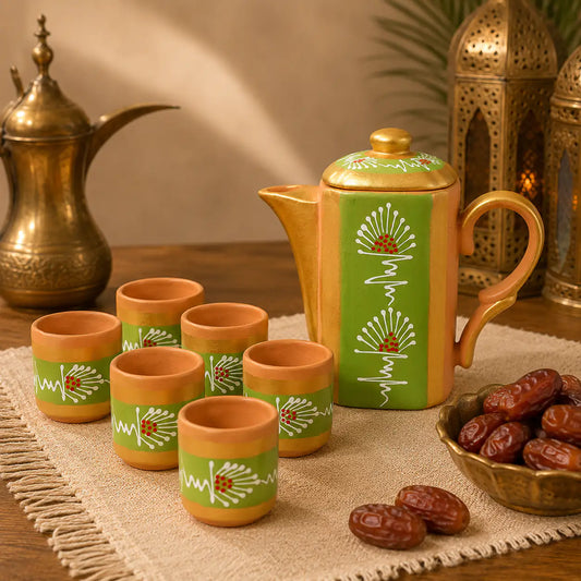Terracotta teapot and cups with green patterns on a wooden table with dates and lanterns.
