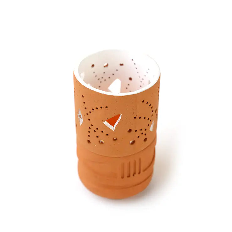 Terracotta-colored candle holder with cut-out design on a white background