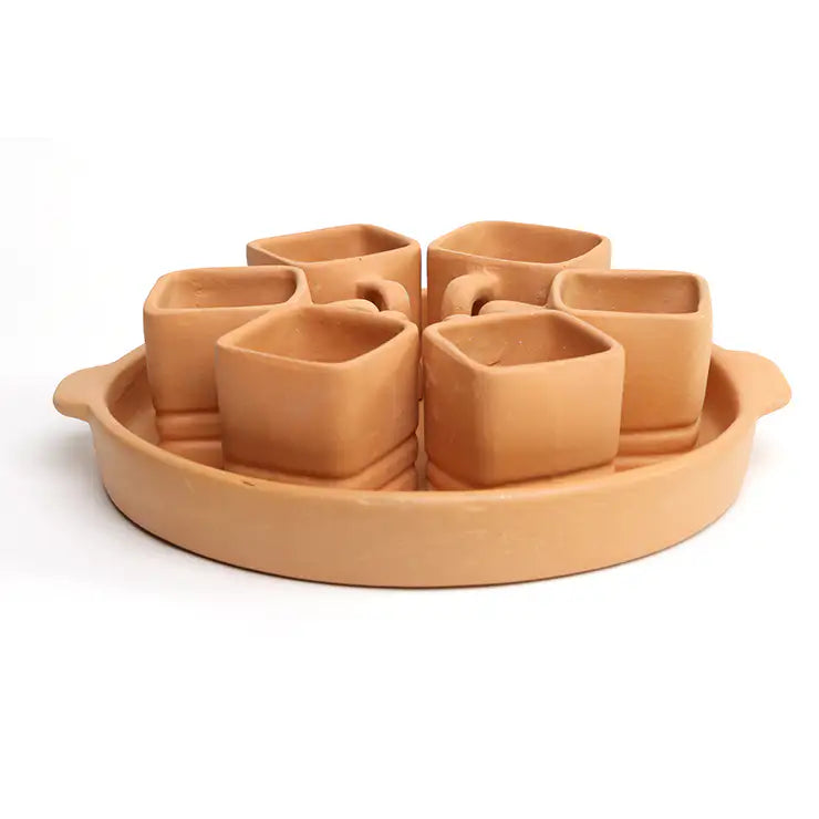 A terracotta clay set of six small square cups arranged in a circular tray with side handles, photographed on a clean white background.