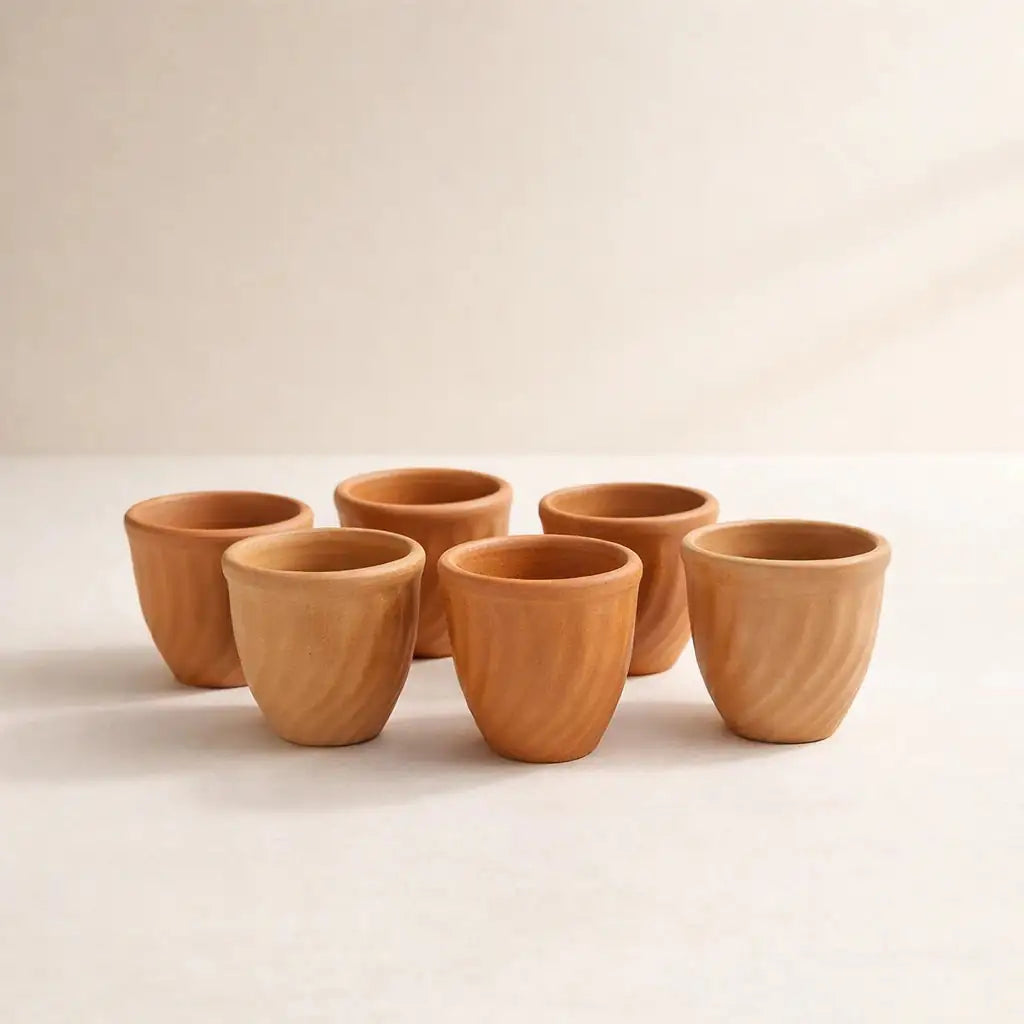Set of six terracotta cups on a beige background