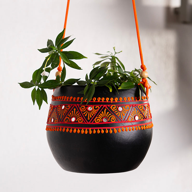 Maison Terracotta hanging planter in matte black with red-orange hand-painted tribal band, suspended with rope cords
