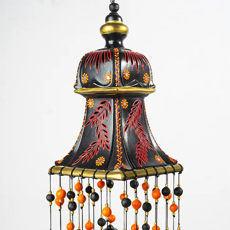 Decorative hanging wind chimes with black, orange, and gold colors on a white background