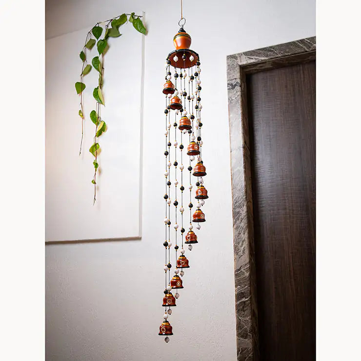 Decorative hanging wind chime with beads against a neutral wall.