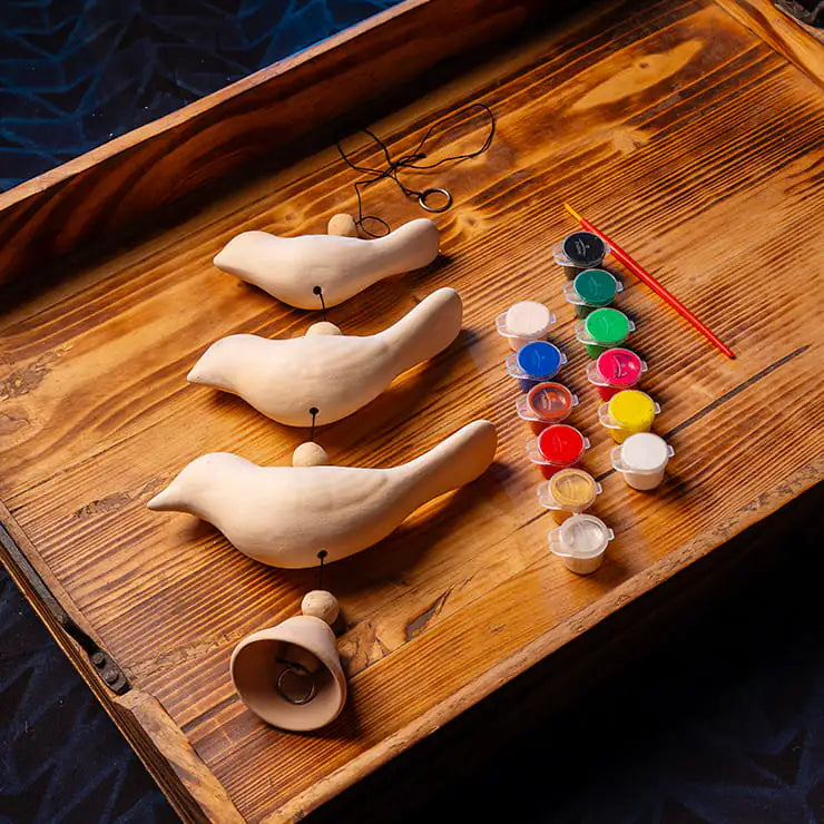 DIY clay bird painting kit for kids with handmade clay birds, paints, brush, beads, cord, and bell
