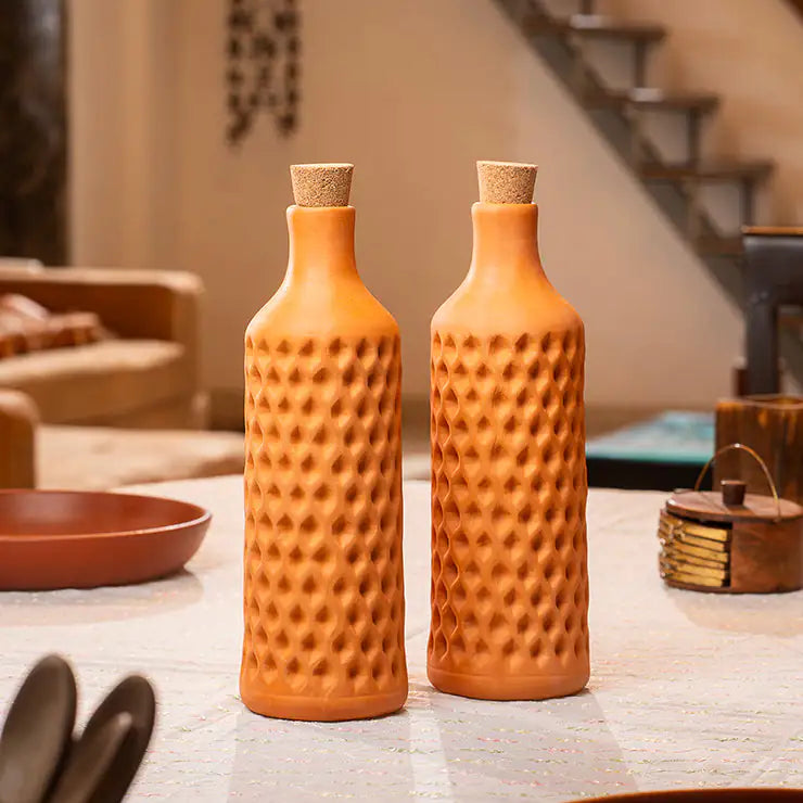 Two terracotta bottles with textured design on a table.