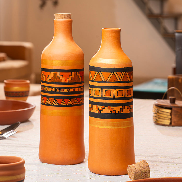 Two terracotta bottles with decorative patterns on a wooden surface.