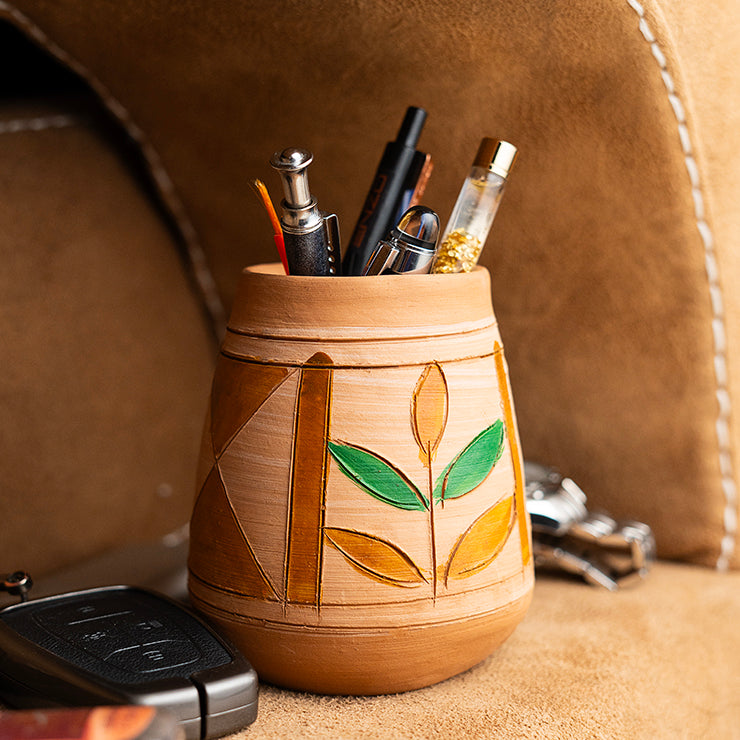 ClayNest handmade terracotta pen stand / desk organizer with hand-painted leaf motif, holding pens on a desk