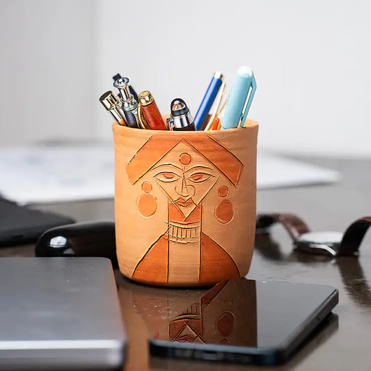 ClayNest handmade terracotta pen stand with carved face-art motif, desk organizer holding pens on a table