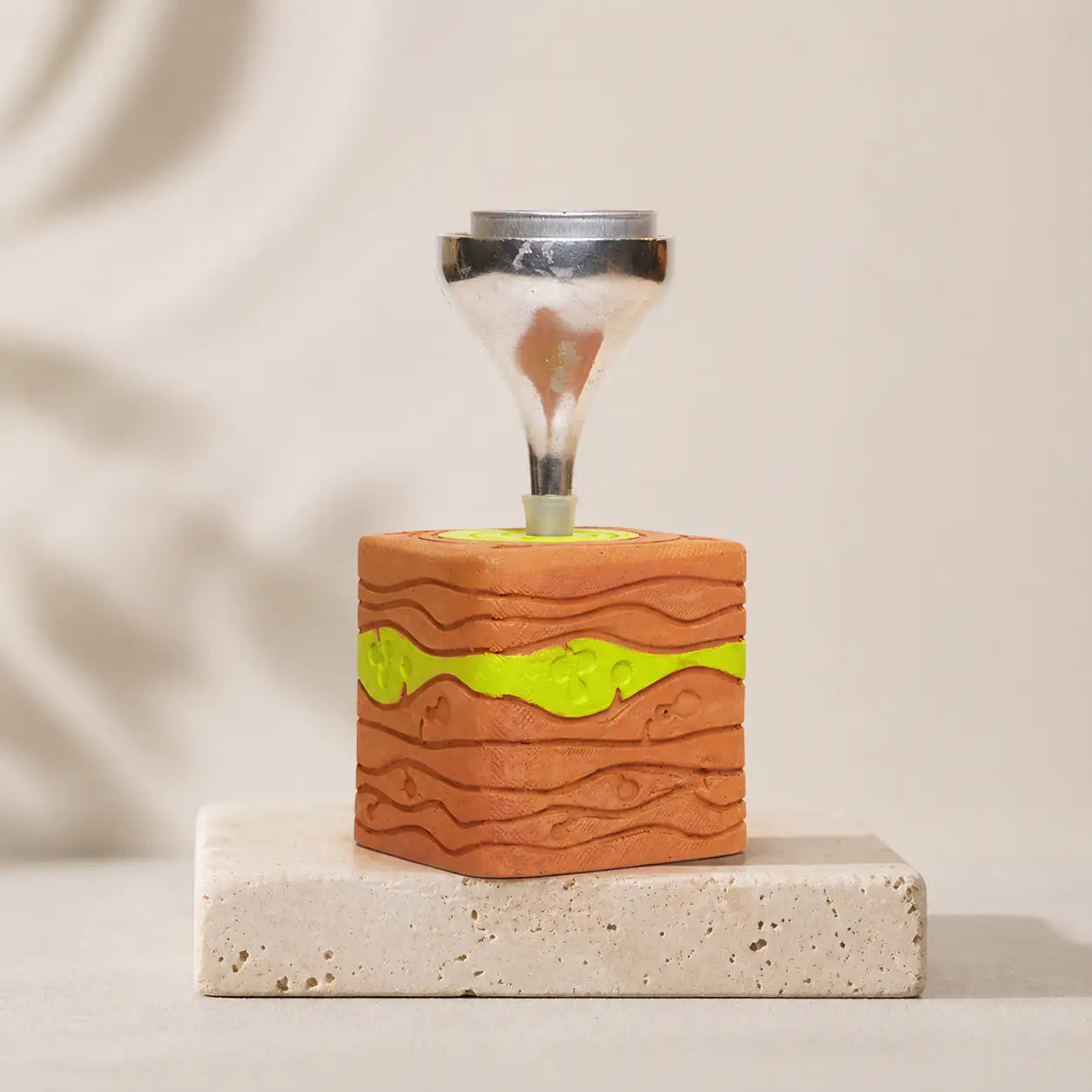 Terracotta square candle stand with raised wave texture on stone surface