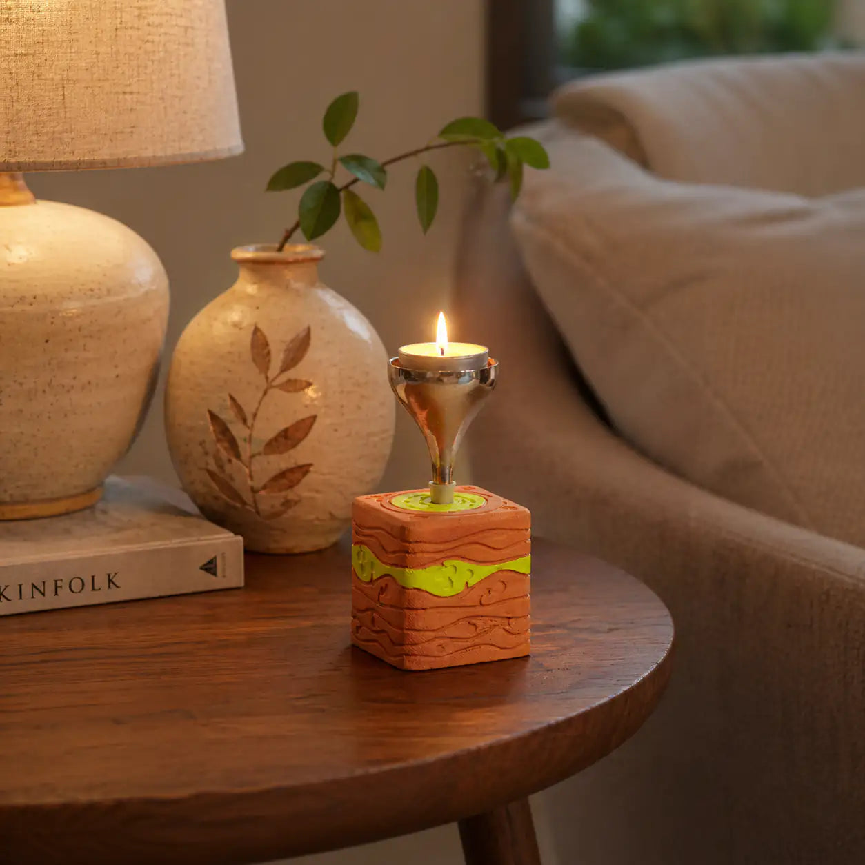 Amour Eclat terracotta candle stand glowing on modern coffee table