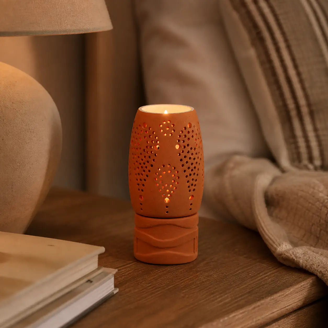 Handmade terracotta lattice tealight holder glowing on wooden table