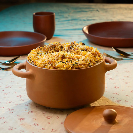 Terracotta pot filled with biryani on a patterned tablecloth