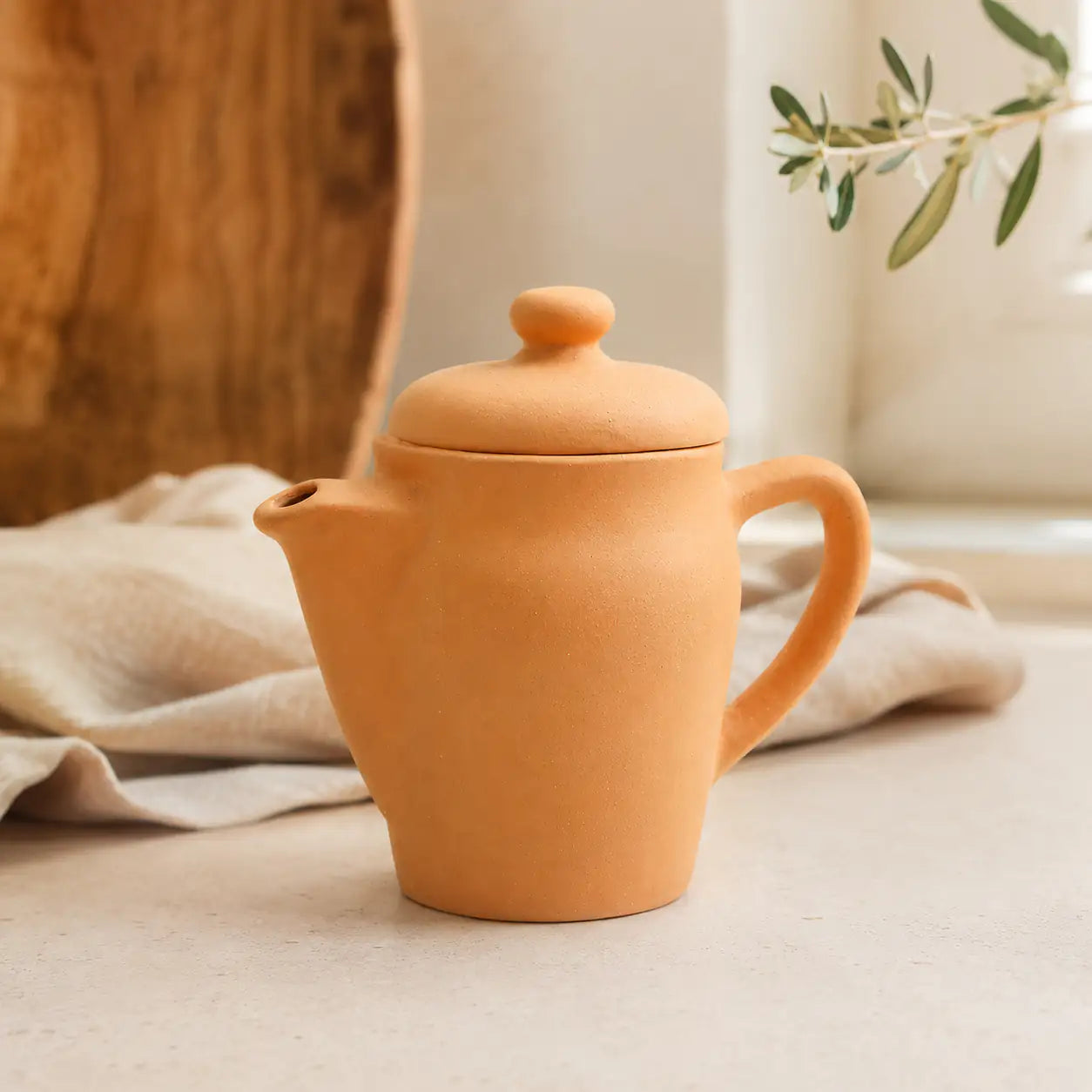 Terracotta teapot on a neutral background with a soft focus