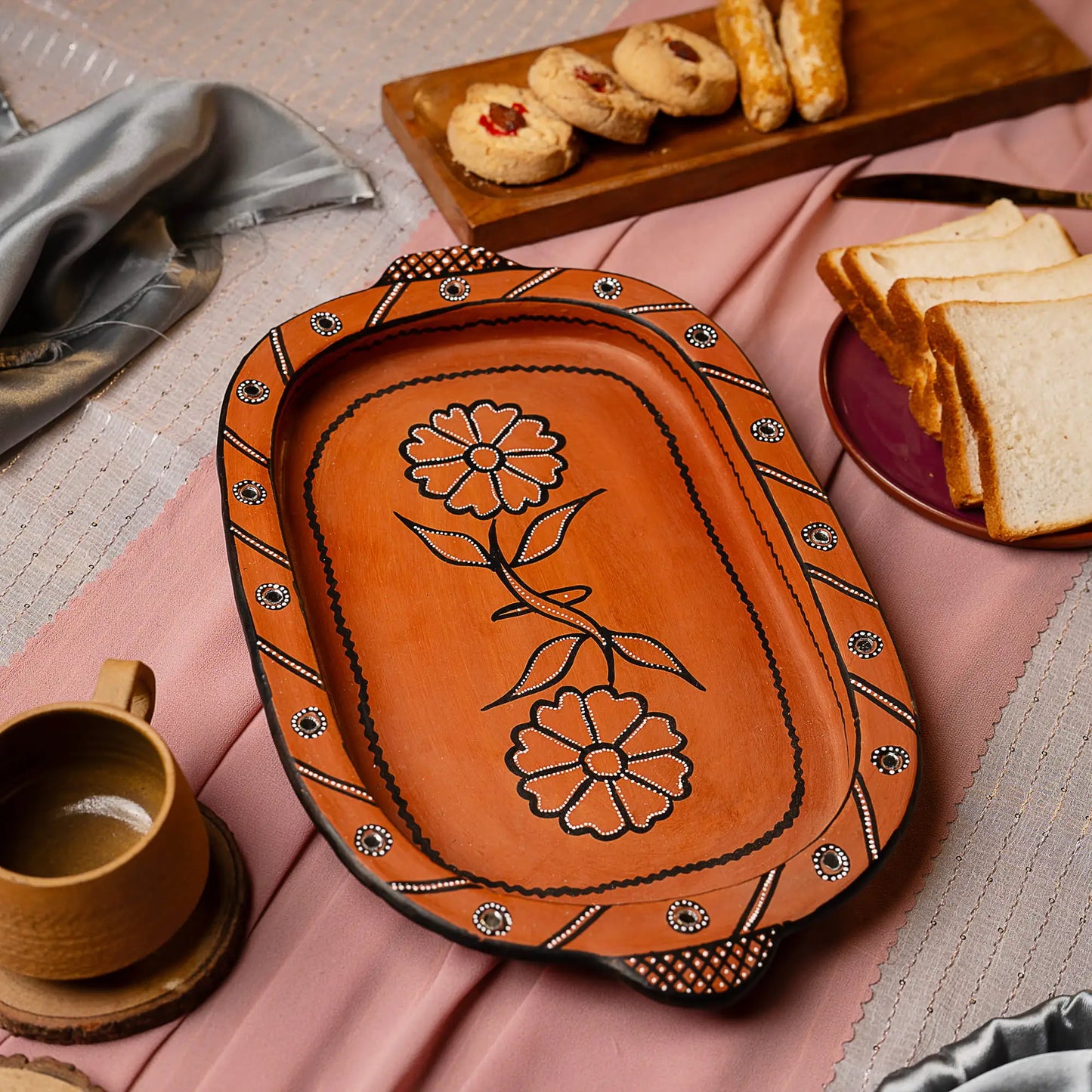 Decorative Terracotta tray with floral design on a table with food and coffee.