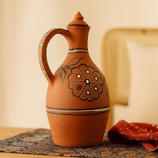Decorative terracotta pot with floral patterns on a wooden surface.