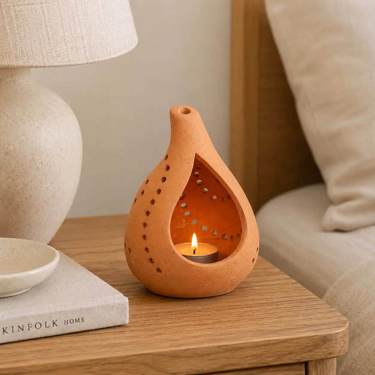 Terracotta droplet candle holder glowing beside vase and home décor