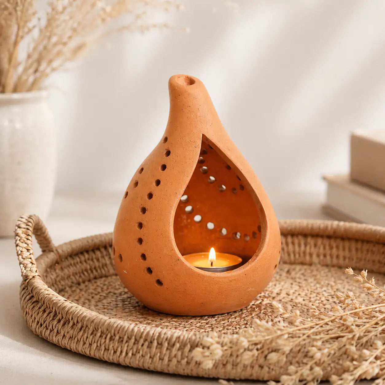 Terracotta candle holder placed on woven tray with tealight candle