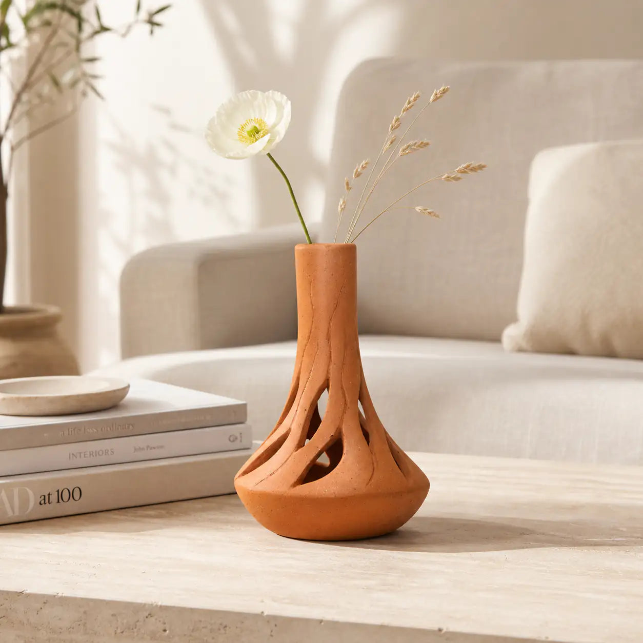 Tall terracotta vase with root-inspired open base and white flower styling