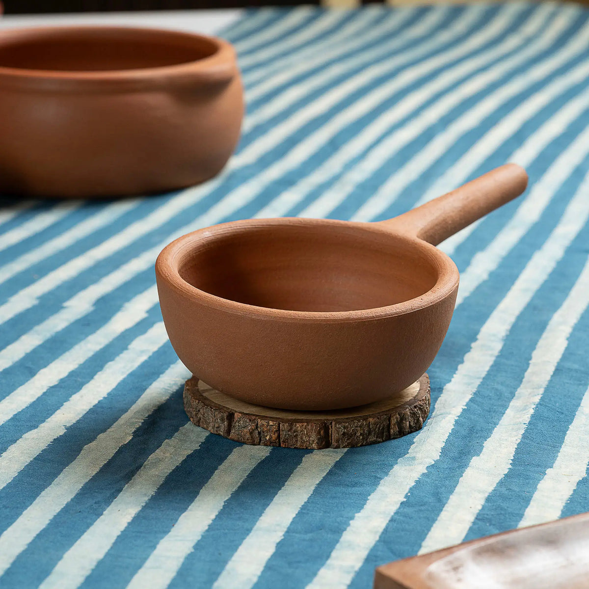 Small natural terracotta saucepan with handle styled on dining table