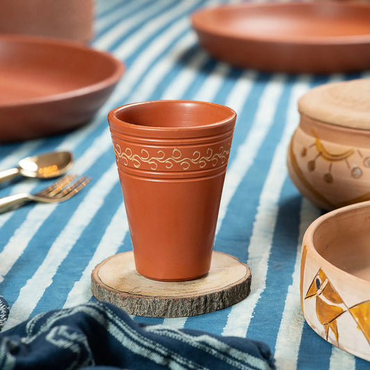 Terracotta drinking glass styled on dining table with handmade clay serveware