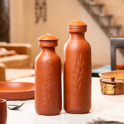 Two terracotta bottles with engraved designs on a table.