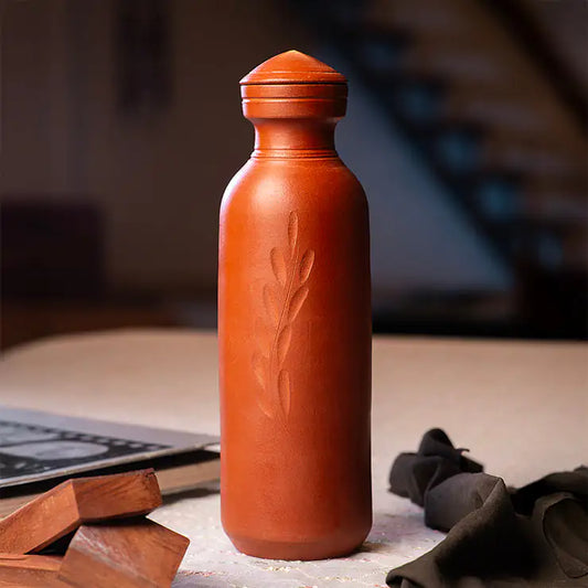 Terracotta water bottle with embossed design on a wooden surface