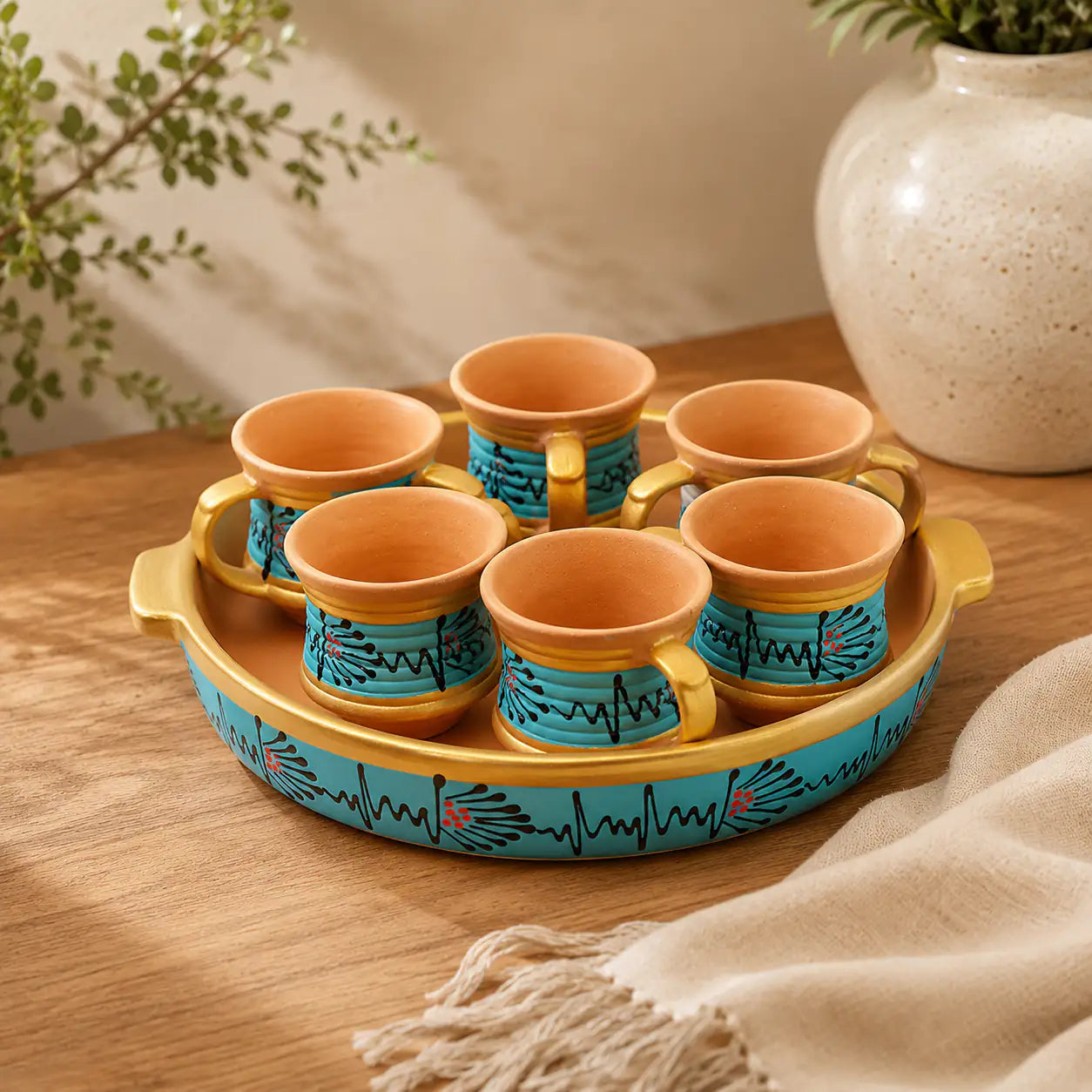 Set of Clay cups with a decorative tray on a wooden surface