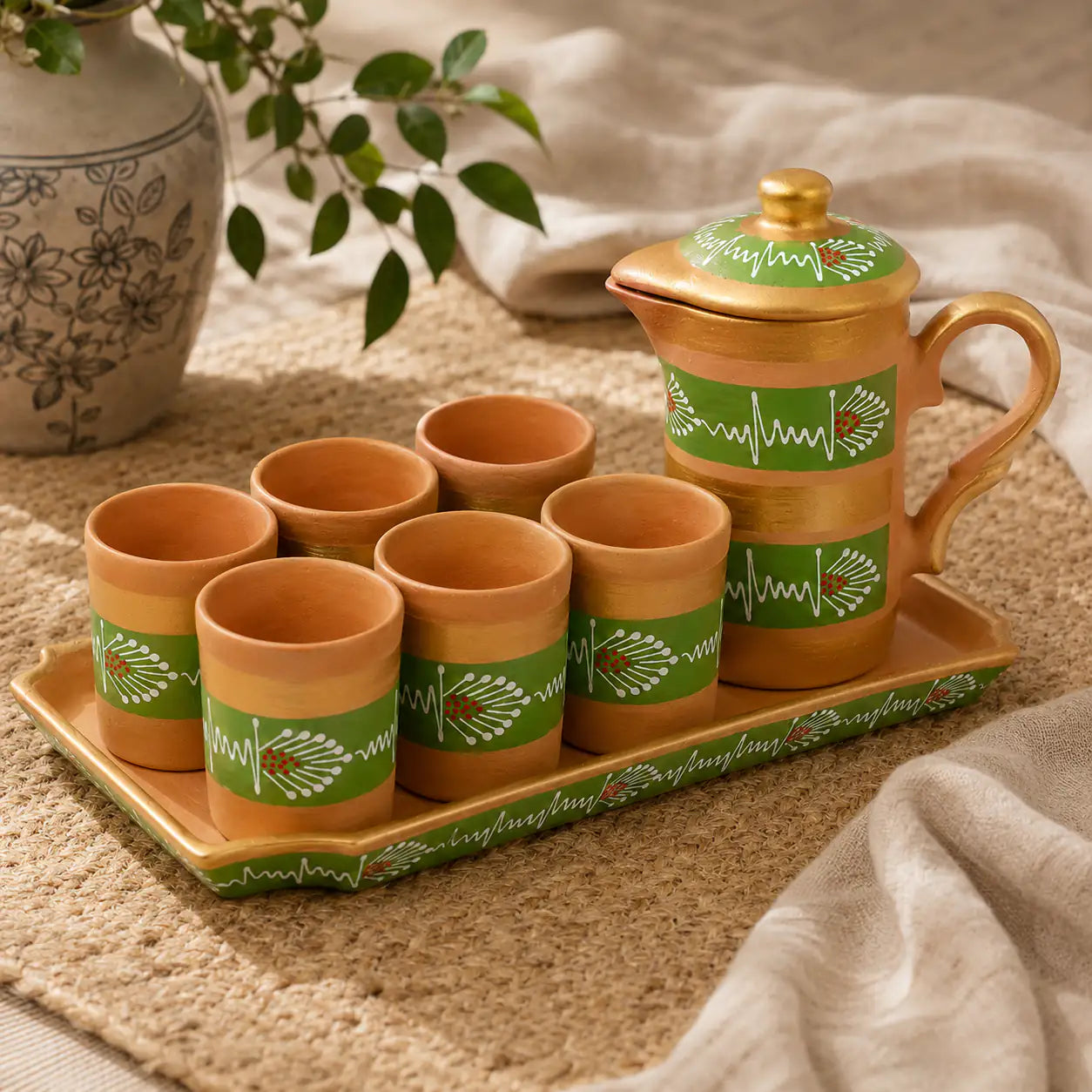 Clay tea set with cups and a teapot on a tray, featuring green patterns.