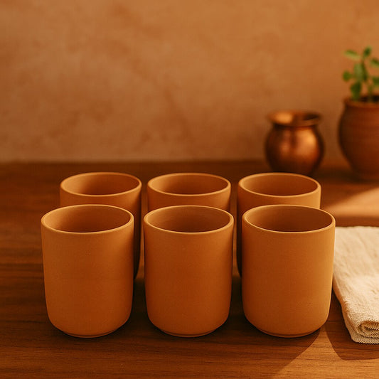 Set of six terracotta cups on a wooden surface with a warm background