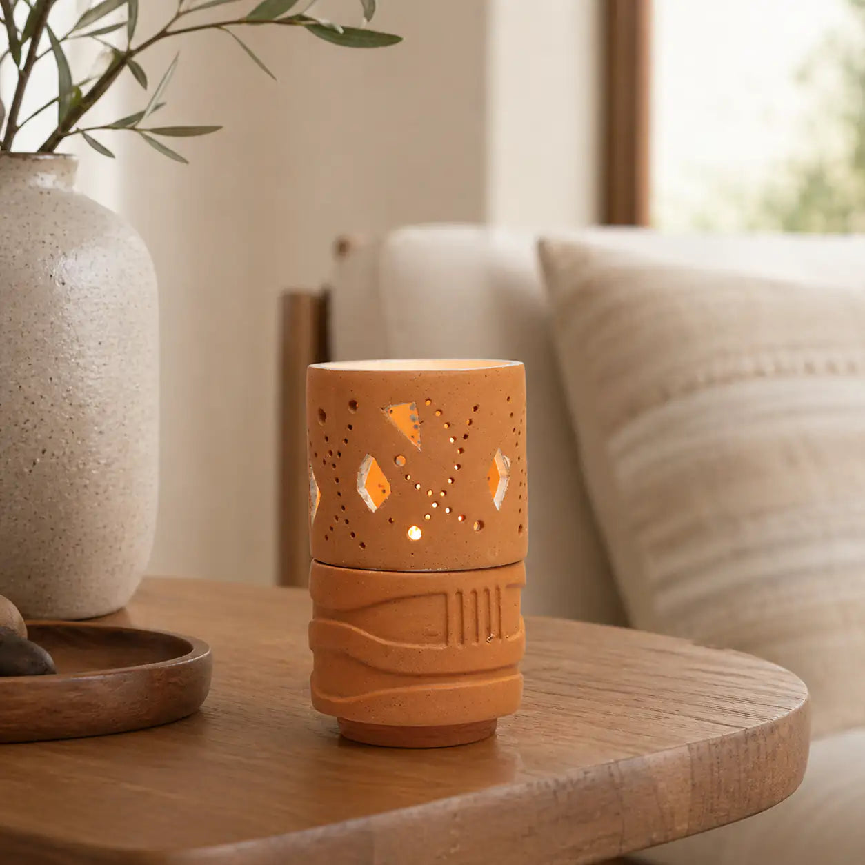 Handmade terracotta geometric tealight holder glowing on bedside table