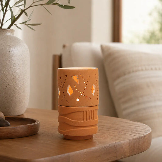 Handmade terracotta geometric tealight holder glowing on bedside table